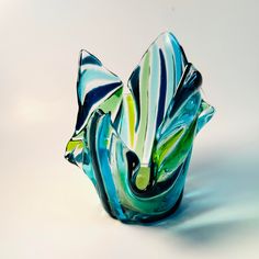 a glass vase sitting on top of a white table covered in green and blue swirls