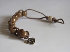 a brown bracelet with a heart charm on the end and a cord attached to it