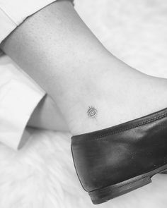 a woman's foot with a small sun tattoo on the left side of her ankle