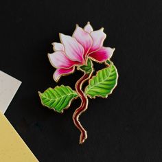 Quick Overview: Size: 1.75" Tall Theme: Floral - Magnolia Color: Soft Pink and White Material: Premium Quality Enamel. Utilizes UV printing, a technique that allows us to capture more intricate details compared to traditional enamel methods. Description: Step into a world of elegance with the "Magnolia (Pink) Enamel Pin." This beautifully crafted pin, standing at 1.75" tall, showcases the delicate beauty of a magnolia flower in a soft, serene shade of pink. The pin is made from premium quality enamel, ensuring a lustrous finish that brings the gentle essence of the magnolia to life. Symbolism: The magnolia flower, known for its grace and ancient beauty, symbolizes dignity, nobility, and a love of nature. Wearing this pin is not only a fashion statement but also a reflection of these timele Plant Enamel Pin, State Flowers, Magnolia Colors, Pink Magnolia, Enamel Pin Collection, Magnolia Blossom, Floral Pins, Ancient Beauty, Magnolia Flower