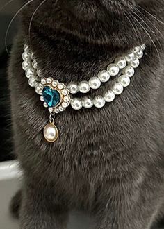 the cat is wearing a necklace with pearls and jewels on it's neck,