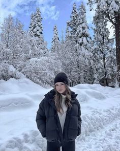 a woman standing in the snow next to some trees