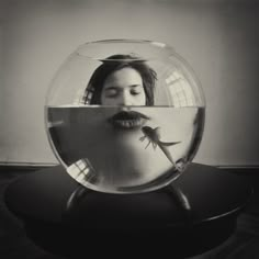 a woman's face is reflected in a fish bowl