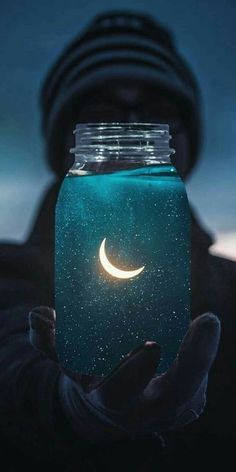 a person holding a jar with the moon in it