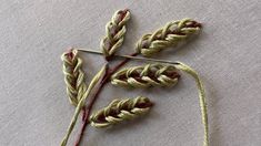 two crocheted stalks of wheat sitting on top of a piece of cloth