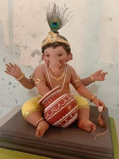 an elephant statue sitting on top of a table with a decorative headpiece in it's lap