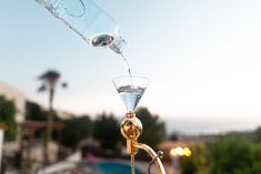 a glass being filled with water from a faucet in front of a swimming pool