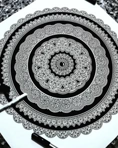 an artistic drawing with black and white ink on paper, depicting a circular design in the center