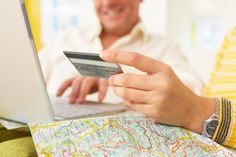 a man holding a credit card while using a laptop