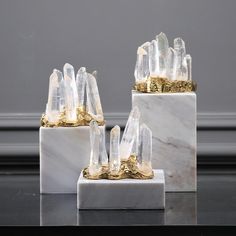 three pieces of white marble with gold accents on each side and one piece of clear quartz in the middle