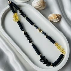 two necklaces on a white tray next to shells