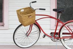 a red bicycle with a basket parked in front of a building