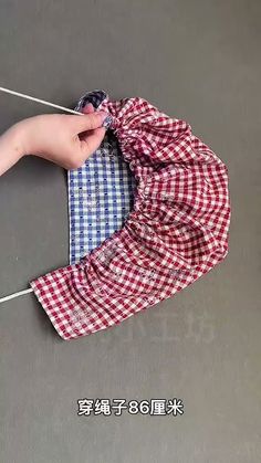 a person is tying a red and white checkered shirt on a clothes hanger