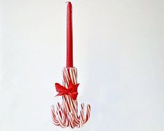 a candy cane candle is hanging from a red ribbon