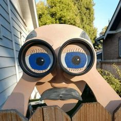 a close up of a person's face with large blue eyes looking over a wooden fence