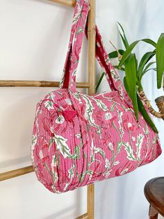 a pink bag hanging from a wooden rack next to a potted plant on a wall