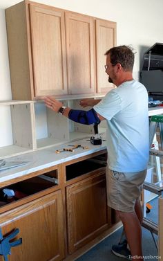 a man is fixing the cabinets in his kitchen with a blue cloth on it's arm