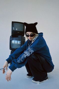 a person kneeling down with a cat hat on and an old tv in the background