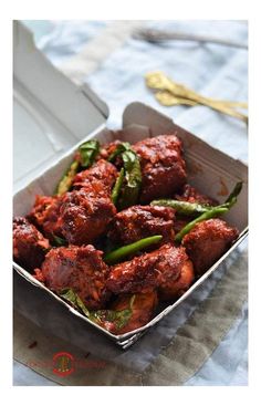 a close up of a box of food with meat and vegetables in it on a table