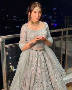 a woman standing on top of a building wearing a dress and holding a cell phone