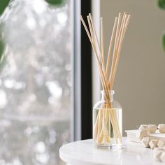 reed diffuses in a glass bottle on a table next to marshmallows