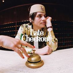 a woman sitting at a table with a bell in front of her and the words late checkout written on it