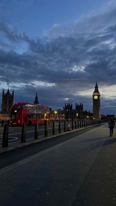 the big ben clock tower towering over the city of london at dusk with people walking on the sidewalk