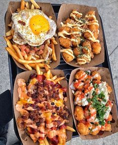 four takeout boxes filled with different types of food on top of a black tray