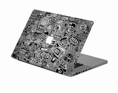 an apple laptop with black and white doodle designs on it's cover is shown