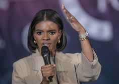 a close up of a person holding a microphone in front of a crowd and raising their hands