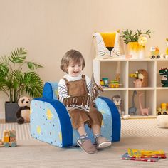 a little boy sitting in a blue chair with toys on the floor next to him