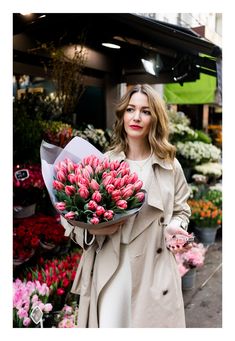 a woman holding a bouquet of pink tulips