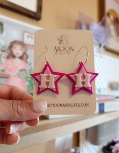 a pair of pink and white star shaped earrings sitting on top of a wooden table