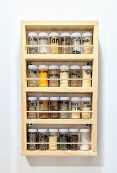 a wooden spice rack with spices and condiments hanging on the wall above it