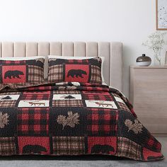 a bed covered in a black and red plaid comforter with an elephant on it