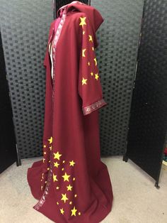 a robe with gold stars on it sitting in front of a wall and two black speakers