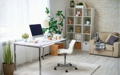 a white desk with a laptop on it in front of a window and a couch