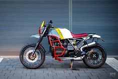 a motorcycle parked in front of a garage door with a red and white seat on it