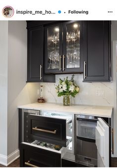 a kitchen with black cabinets and white marble counter tops, an icebox in the center