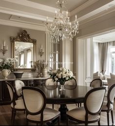 an elegant dining room with chandelier and table in front of large mirror on the wall