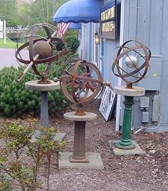 two metal sculptures sitting next to each other in front of a blue building with an umbrella