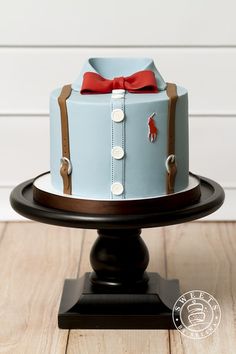 a blue and brown cake with a red bow sitting on top of a wooden table