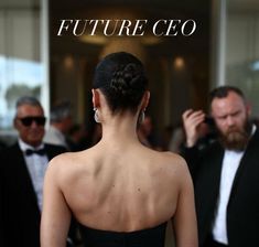 the back of a woman in a black dress at an event with people behind her