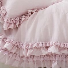 a bed with pink ruffled sheets and pillows