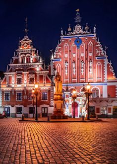 a large red building sitting on top of a cobblestone street next to a tall clock tower