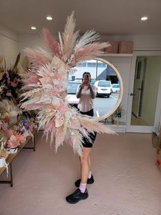 a woman is taking a selfie in front of a mirror with feathers on it