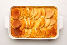 a casserole dish filled with baked potatoes on top of a white countertop