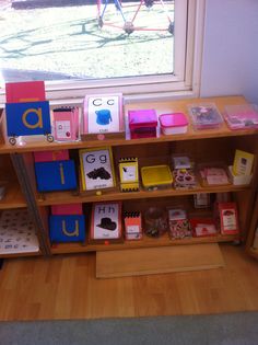 a wooden shelf filled with lots of different types of cards and magnets next to a window