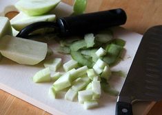 chopped up green apples on a cutting board with a black handled knife next to them