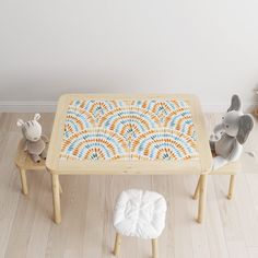 two stuffed animals sitting on stools in front of a table with an orange and blue design